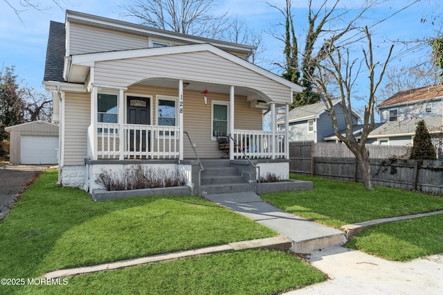 bungalow-style home featuring a garage, a front yard, an outbuilding, and covered porch