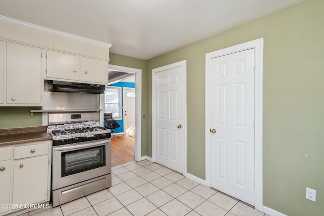 kitchen featuring white cabinets, light tile patterned flooring, and stainless steel gas range