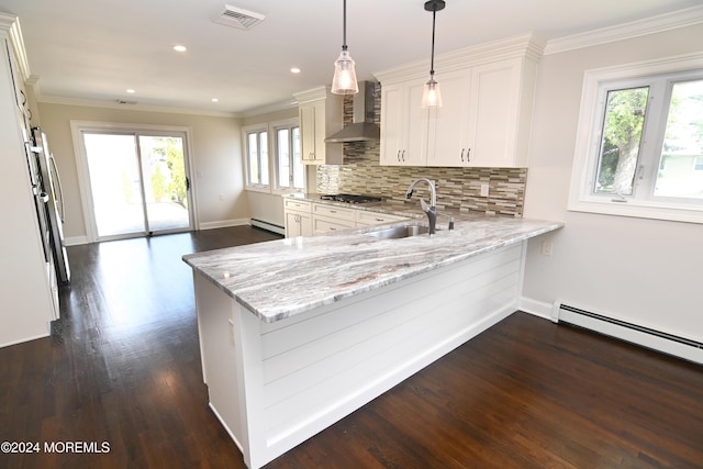 kitchen featuring sink, wall chimney range hood, kitchen peninsula, and decorative light fixtures