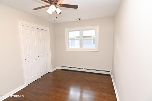 unfurnished bedroom with a baseboard radiator, dark wood-type flooring, ceiling fan, and a closet