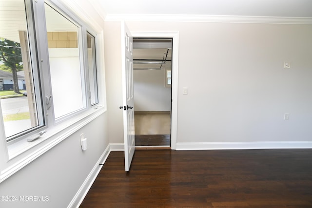 unfurnished bedroom featuring crown molding, a closet, dark hardwood / wood-style floors, and multiple windows