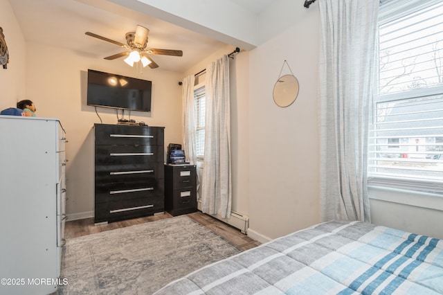 bedroom featuring ceiling fan, light wood-type flooring, and baseboard heating