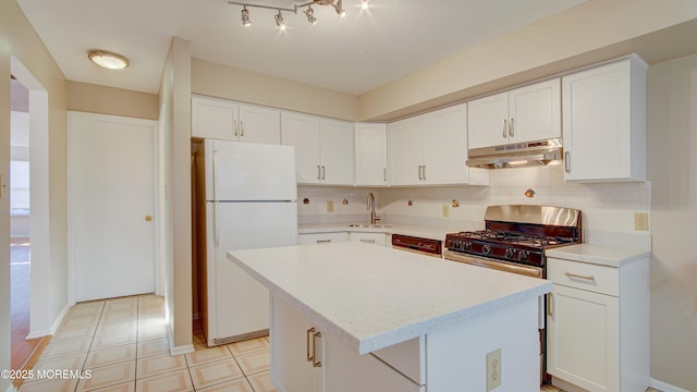 kitchen with white refrigerator, white cabinetry, a kitchen island, and sink