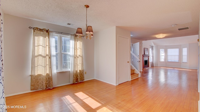 unfurnished room featuring wood-type flooring, a chandelier, and a textured ceiling