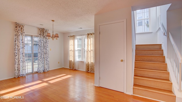 interior space with a chandelier, a textured ceiling, and light wood-type flooring