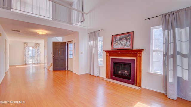 unfurnished living room featuring hardwood / wood-style flooring, a wealth of natural light, and a towering ceiling