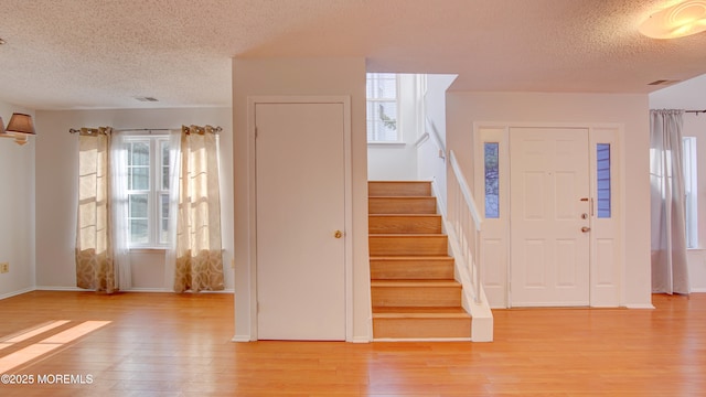 foyer entrance with a textured ceiling and light wood-type flooring