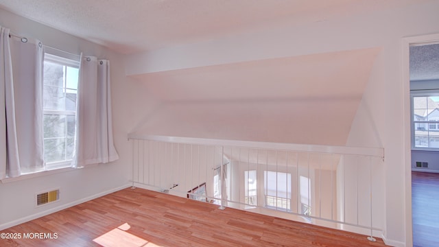 spare room featuring hardwood / wood-style flooring, plenty of natural light, and a textured ceiling