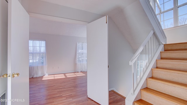 stairway featuring wood-type flooring and vaulted ceiling