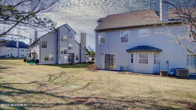 rear view of house featuring central AC and a lawn