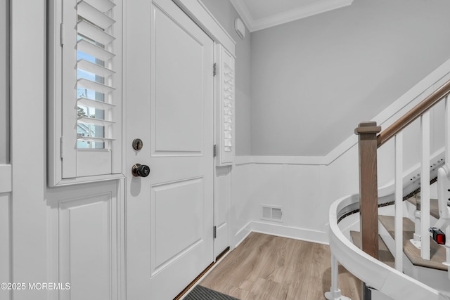 entryway with ornamental molding and light hardwood / wood-style floors