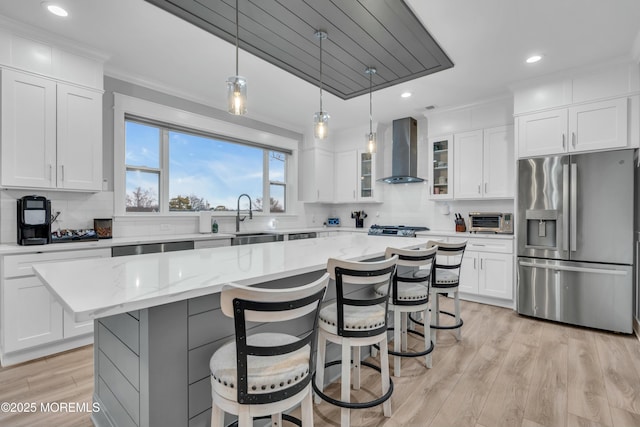 kitchen featuring stainless steel appliances, white cabinetry, a kitchen island, and wall chimney exhaust hood