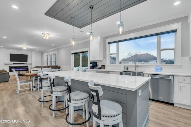 kitchen featuring light stone countertops, dishwasher, a kitchen island, and white cabinets