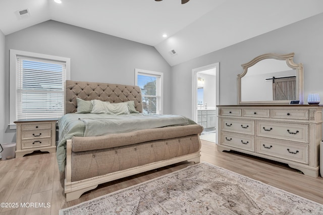 bedroom with ceiling fan, lofted ceiling, ensuite bath, and light hardwood / wood-style flooring