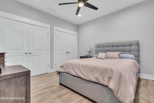 bedroom featuring ceiling fan, two closets, and light wood-type flooring