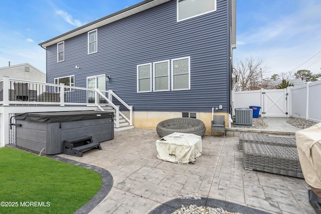 rear view of property featuring cooling unit, a hot tub, and a patio area