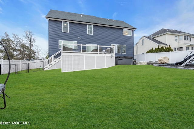 back of property with a hot tub, a wooden deck, and a yard