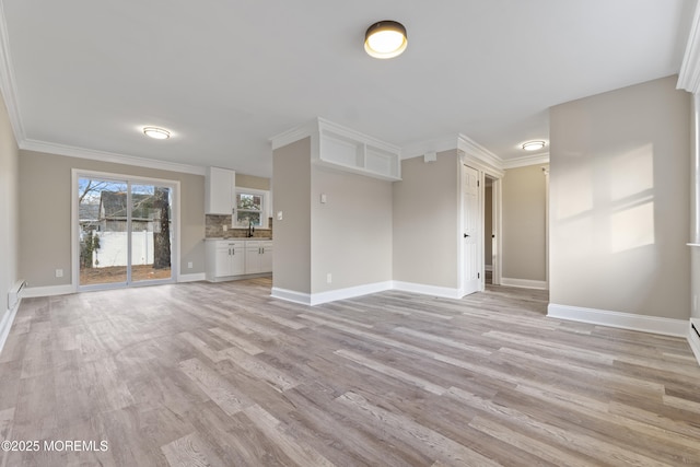 unfurnished living room with crown molding, sink, and light hardwood / wood-style floors