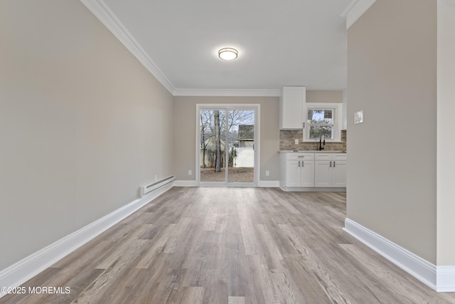 interior space with ornamental molding, baseboard heating, and light hardwood / wood-style flooring