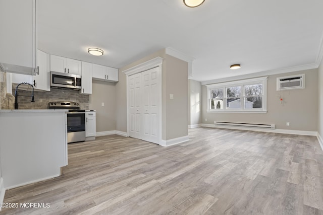 kitchen featuring sink, a wall unit AC, white cabinets, stainless steel appliances, and a baseboard heating unit