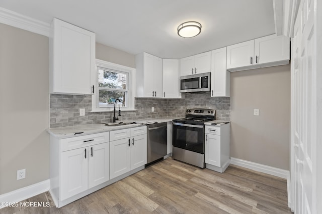 kitchen featuring appliances with stainless steel finishes, sink, white cabinets, and light hardwood / wood-style floors