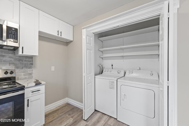 laundry area with washing machine and clothes dryer and light wood-type flooring