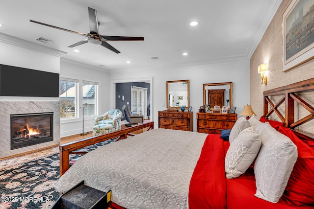 bedroom with crown molding, wood-type flooring, ceiling fan, and a fireplace