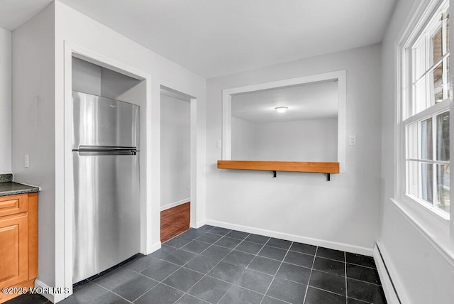 kitchen with baseboard heating, stainless steel fridge, and dark tile patterned flooring