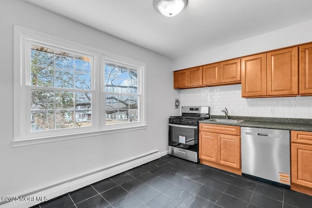 kitchen featuring appliances with stainless steel finishes, sink, backsplash, dark tile patterned floors, and a baseboard heating unit