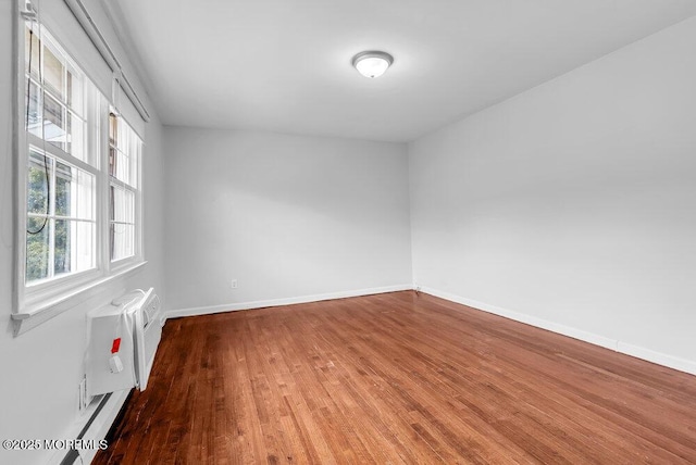 unfurnished room featuring a wall mounted air conditioner and hardwood / wood-style flooring