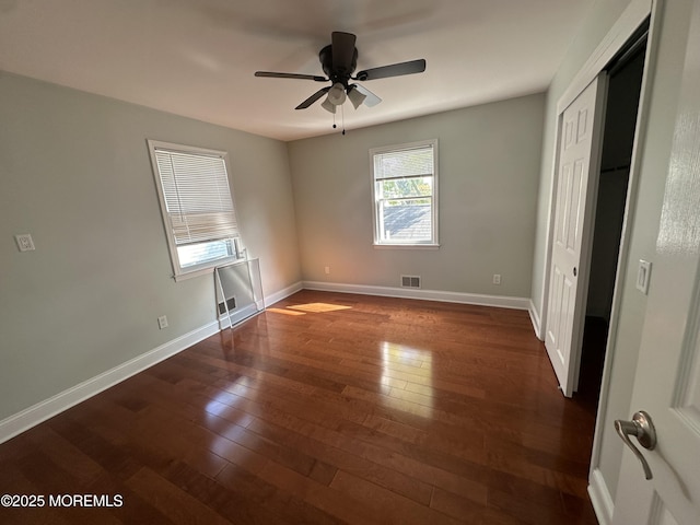 unfurnished bedroom with dark hardwood / wood-style flooring, a closet, and ceiling fan