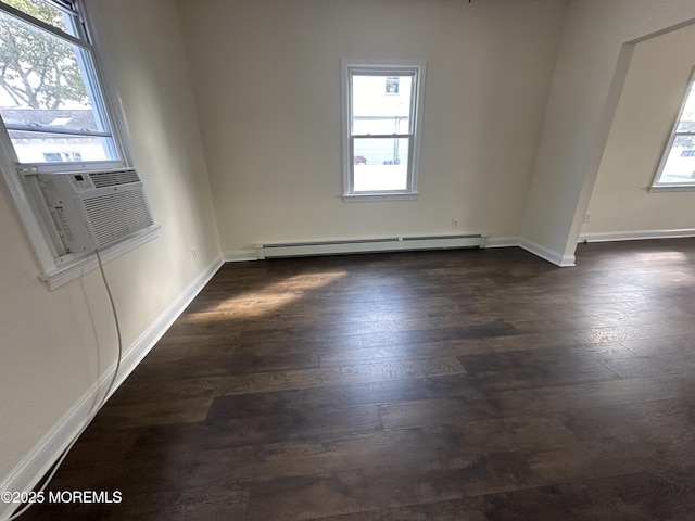 spare room with dark hardwood / wood-style floors, a healthy amount of sunlight, and baseboard heating