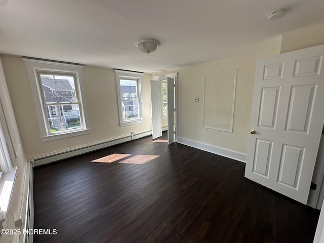 unfurnished room with baseboard heating and dark hardwood / wood-style floors