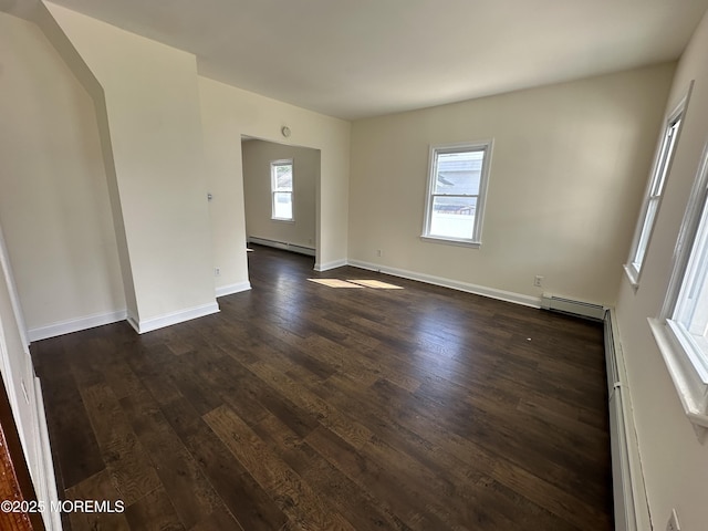 unfurnished room with a baseboard heating unit and dark wood-type flooring