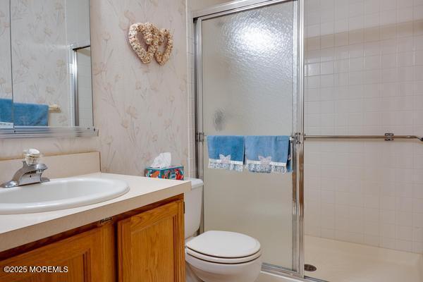 bathroom with a shower with door, vanity, and toilet