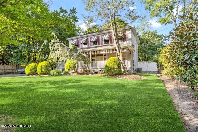 view of front of property with central AC, a front lawn, and covered porch