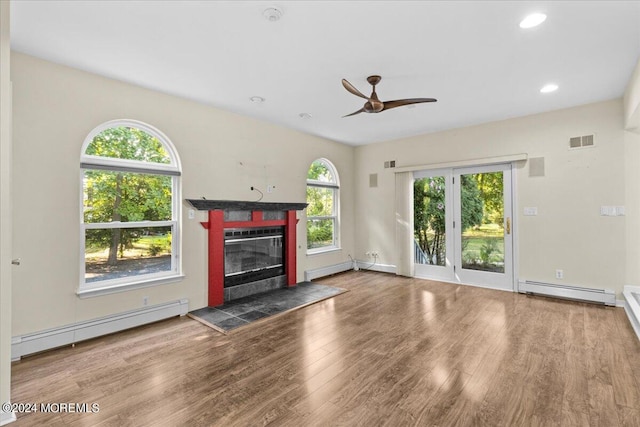 unfurnished living room with ceiling fan, a baseboard radiator, a tile fireplace, and wood-type flooring