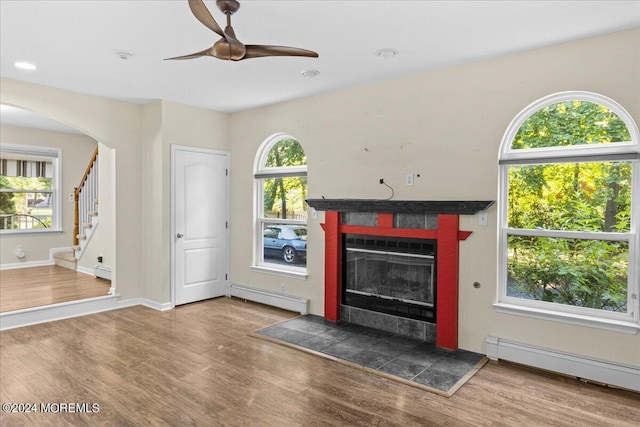 unfurnished living room featuring hardwood / wood-style flooring, a baseboard radiator, and a tile fireplace