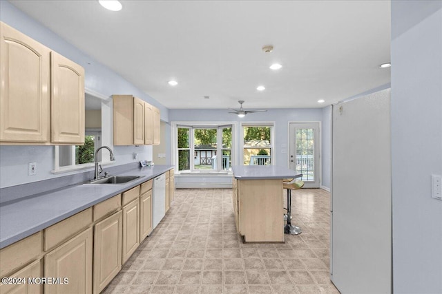 kitchen with sink, dishwasher, a center island, a kitchen bar, and light brown cabinets