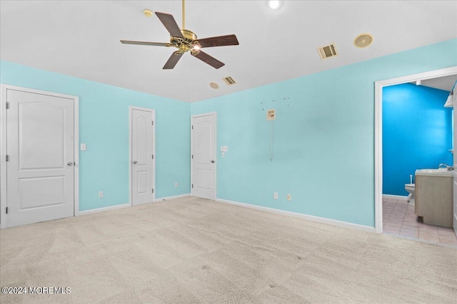 unfurnished bedroom with light carpet, connected bathroom, and ceiling fan