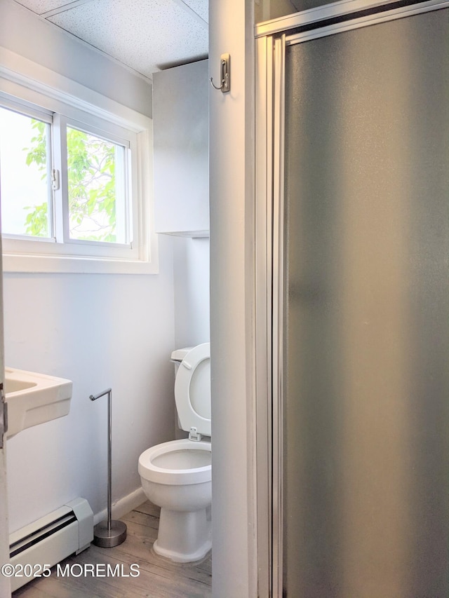 bathroom with hardwood / wood-style floors, walk in shower, toilet, and baseboard heating