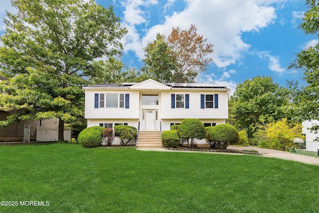 bi-level home featuring a front lawn and solar panels