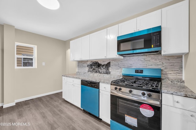 kitchen featuring stainless steel appliances, white cabinetry, and light stone counters