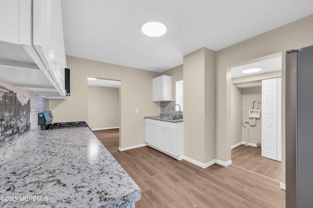 kitchen with range, sink, light hardwood / wood-style flooring, and white cabinets