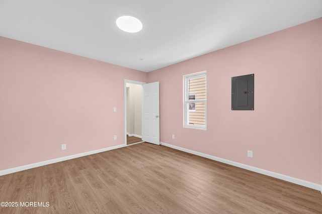 spare room featuring electric panel and light wood-type flooring