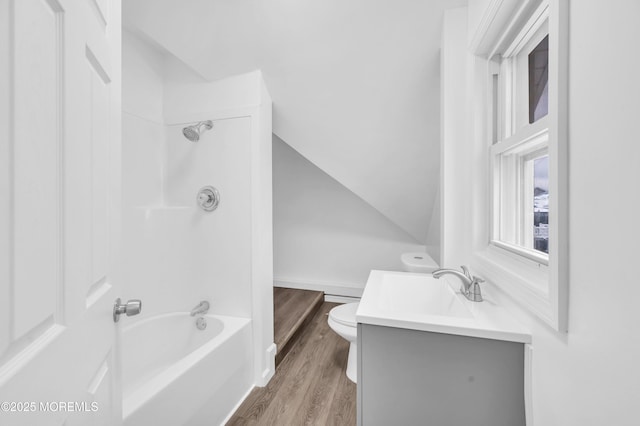 full bathroom featuring vaulted ceiling, hardwood / wood-style floors, vanity, toilet, and bathing tub / shower combination