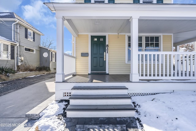 snow covered property entrance featuring a porch