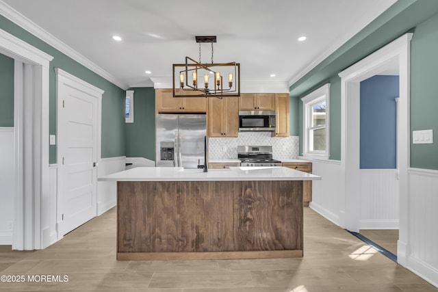 kitchen featuring crown molding, a center island, hanging light fixtures, light hardwood / wood-style flooring, and stainless steel appliances