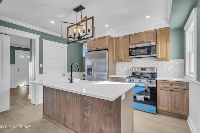 kitchen featuring appliances with stainless steel finishes, decorative light fixtures, a kitchen island with sink, and sink