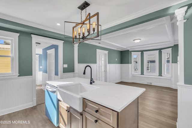 kitchen featuring light brown cabinetry, decorative light fixtures, an island with sink, dishwasher, and light hardwood / wood-style flooring